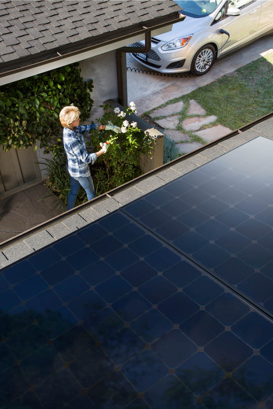 A woman walking outside her house that is using solar energy.