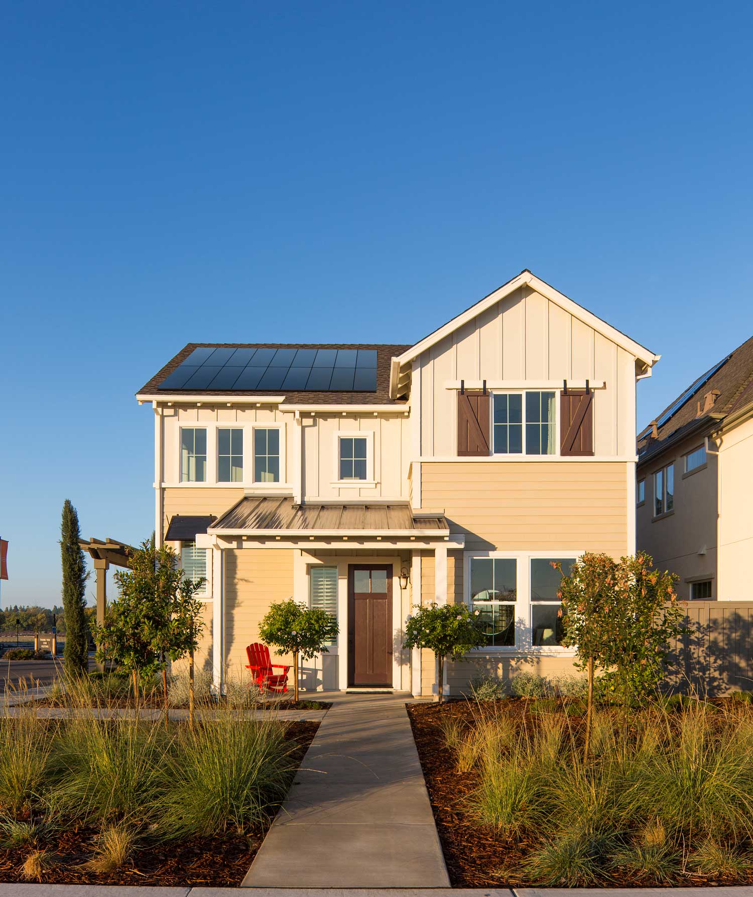 A white cottage home with solar panels installed on the roof.